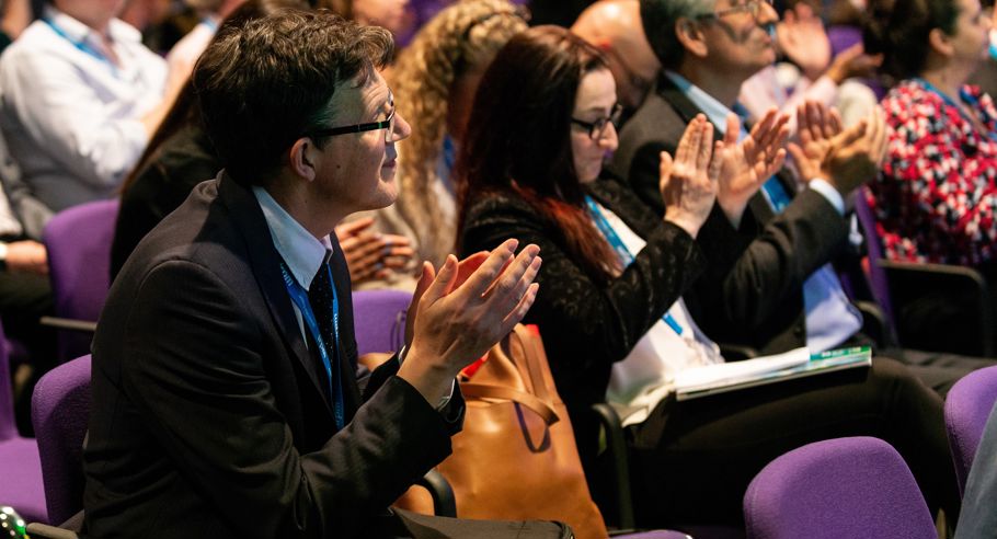 A row of people at a property managers industry event clapping